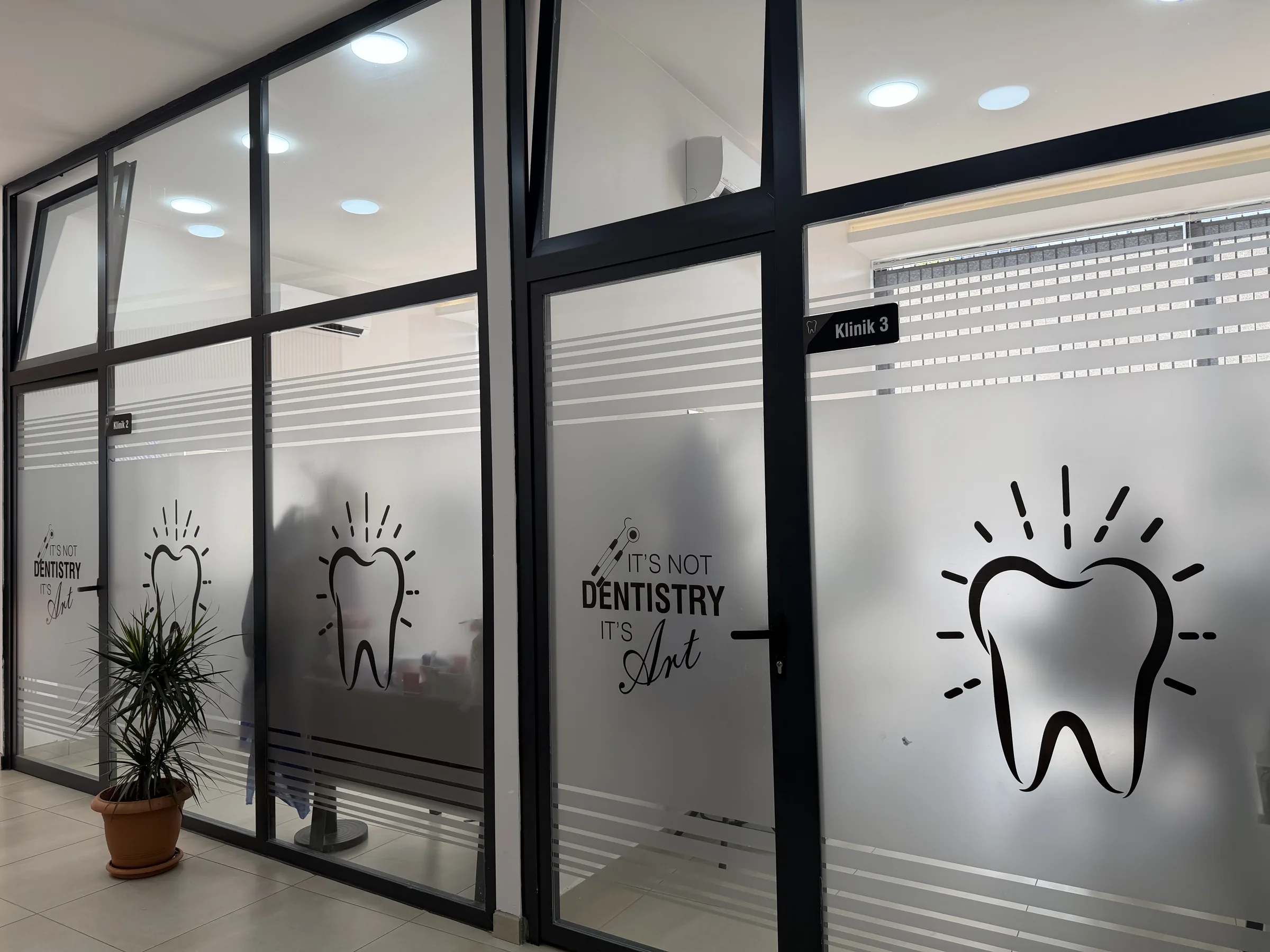 Klinik odalarının buzlu cam kapıları — diş motifli koridor