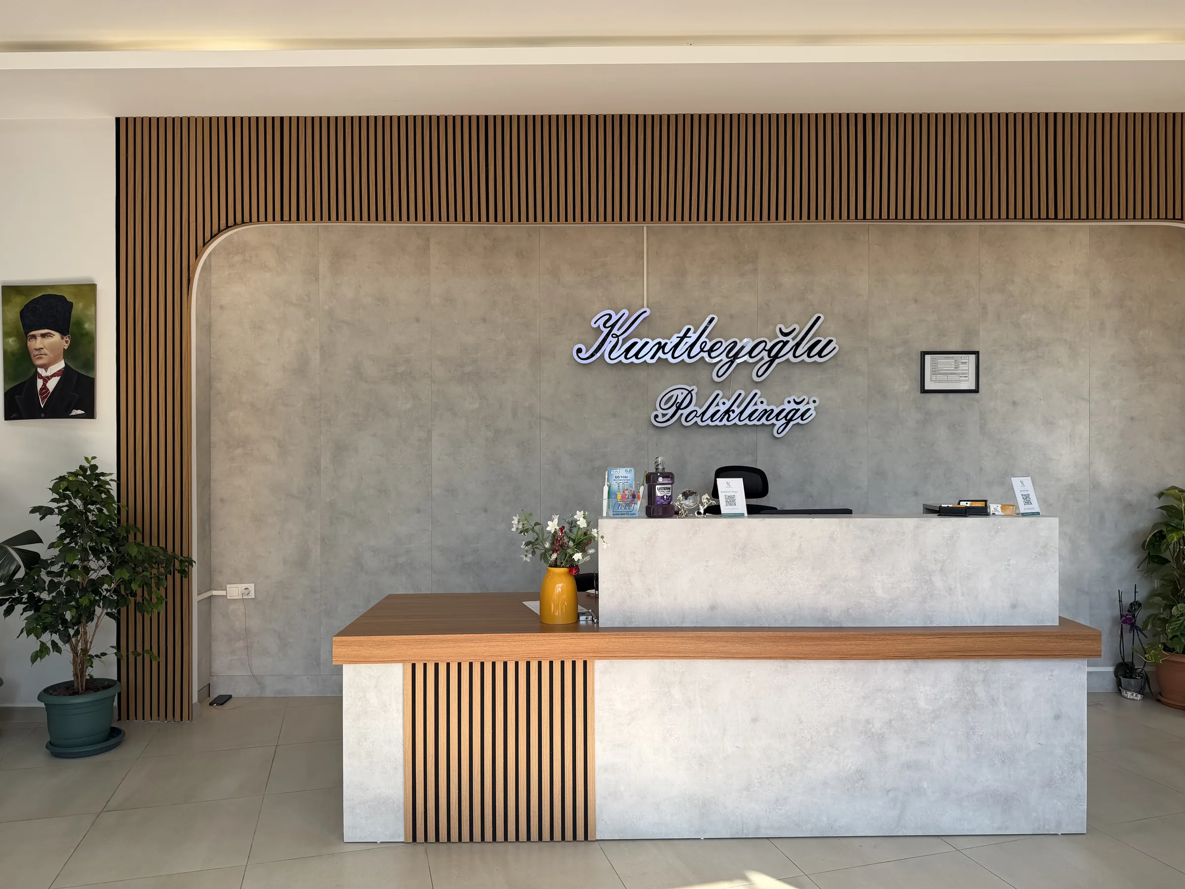 Klinik resepsiyonu — el yazısı ışıklı tabela ve ahşap panel duvar